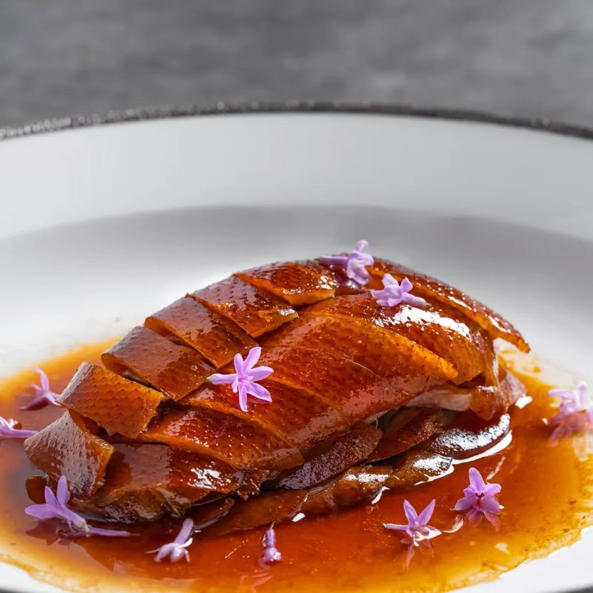 A plated course of Peking duck in a fine-dining dining room